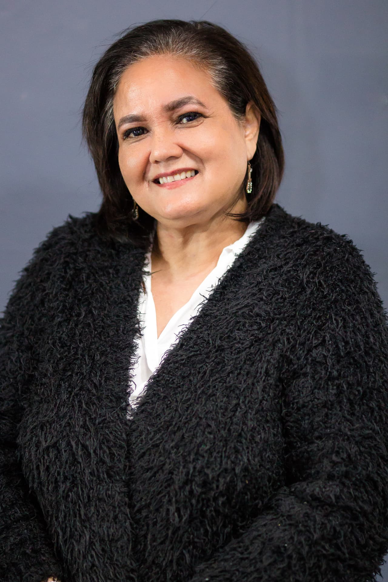 Feroza Miller-Isaacs, smiling in a black cardigan over a white blouse